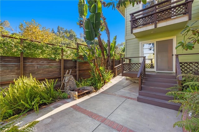 view of patio featuring fence and a balcony