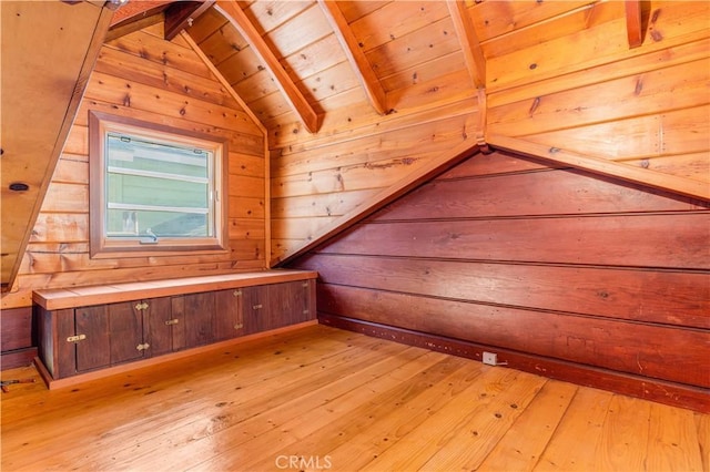 additional living space with lofted ceiling with beams, light wood-style flooring, wood walls, and wooden ceiling