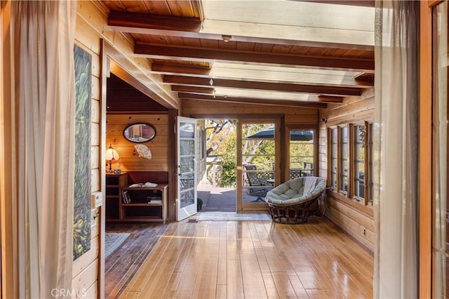 sunroom featuring wooden walls, wooden ceiling, beamed ceiling, and hardwood / wood-style flooring