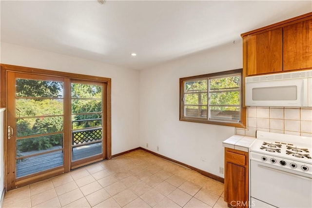 kitchen with tile counters, baseboards, brown cabinets, and white appliances