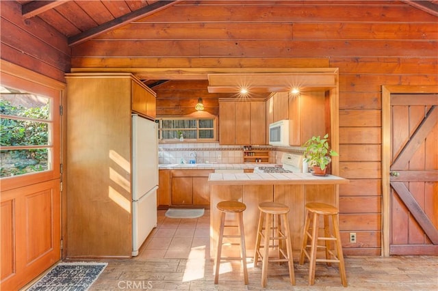 kitchen with white appliances, wood walls, tile countertops, a peninsula, and wood ceiling