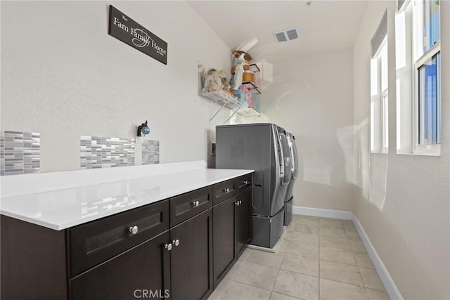 washroom featuring baseboards, washer and clothes dryer, cabinet space, and light tile patterned floors