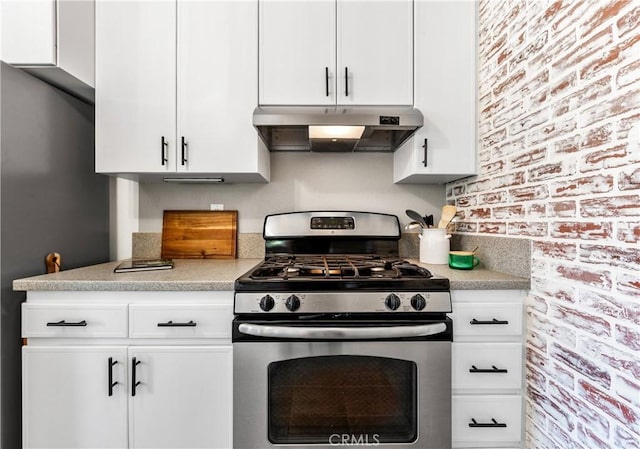 6222 Shawnee Rd, Westminster, CA 92683 - kitchen featuring gas range, under cabinet range hood, light countertops, white cabinets, and brick wall