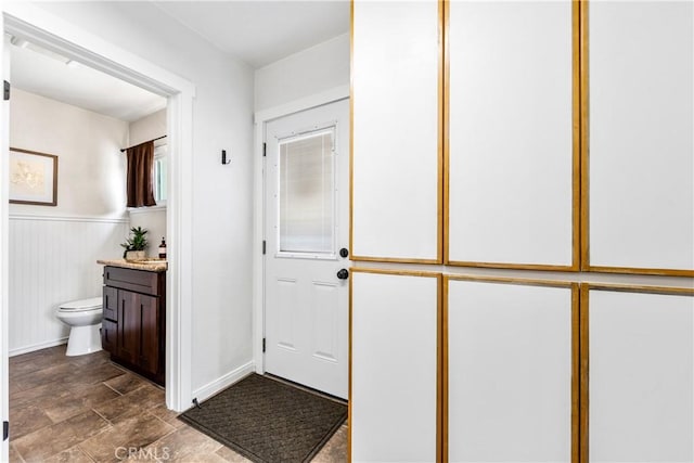 6222 Shawnee Rd, Westminster, CA 92683 - bathroom with toilet, vanity, stone finish floors, baseboards, and a wainscoted wall