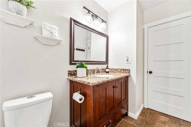 6222 Shawnee Rd, Westminster, CA 92683 - bathroom featuring vanity, toilet, baseboards, and stone finish flooring