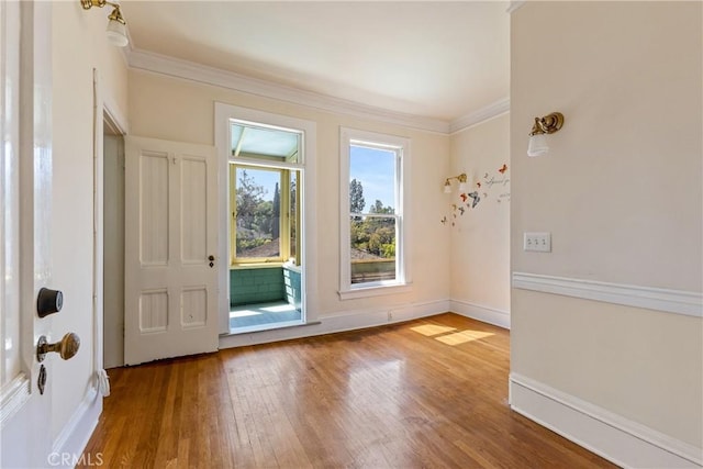 doorway with crown molding, baseboards, and wood finished floors