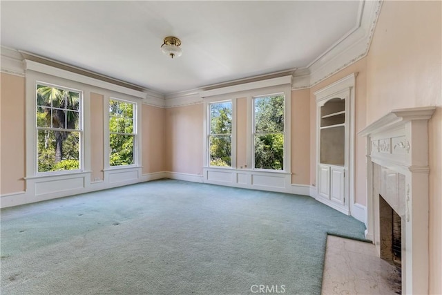 unfurnished living room with crown molding, carpet, a decorative wall, and a premium fireplace