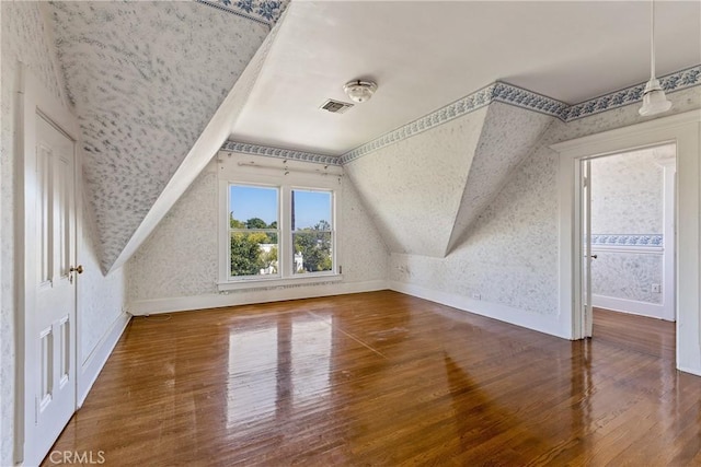 bonus room featuring baseboards, wallpapered walls, vaulted ceiling, visible vents, and hardwood / wood-style flooring