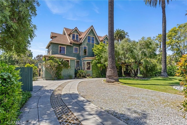 victorian house featuring fence and a front lawn