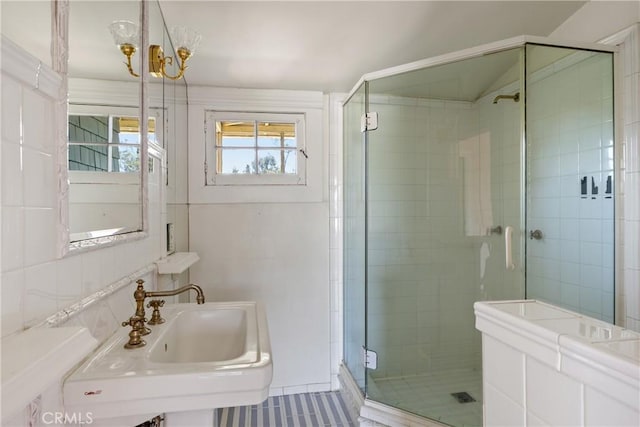 bathroom with a sink, tile walls, tile patterned flooring, and a stall shower