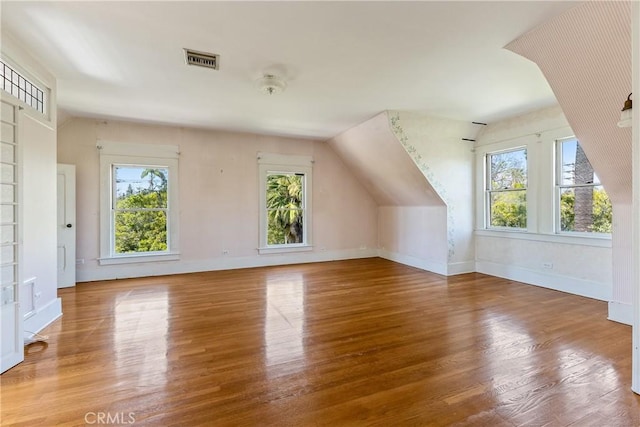 bonus room featuring baseboards, lofted ceiling, wood finished floors, and visible vents