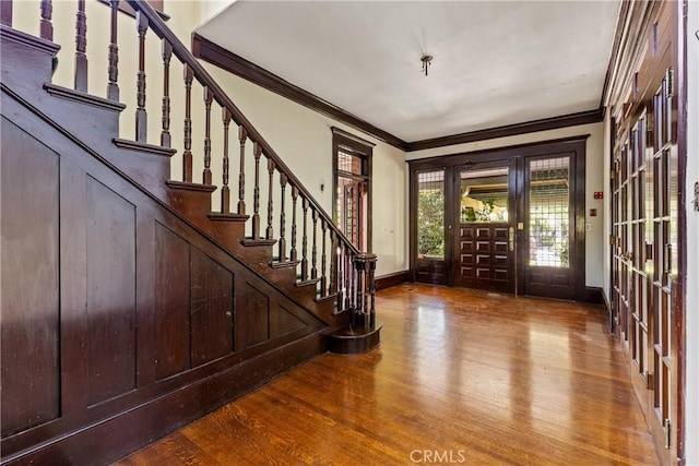 entrance foyer with baseboards, ornamental molding, stairs, and wood finished floors