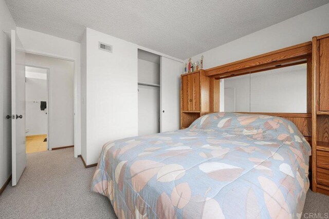 carpeted bedroom with baseboards, a textured ceiling, and visible vents