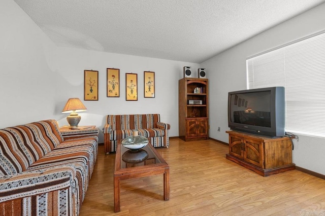 living room featuring a textured ceiling, baseboards, and wood finished floors