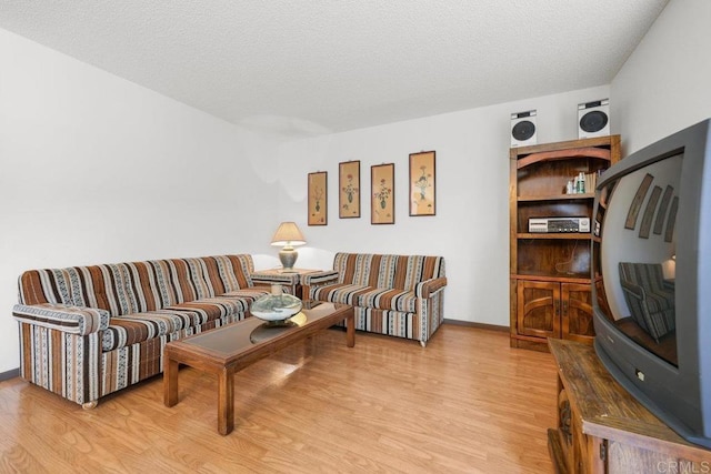 living room featuring light wood-style floors, a textured ceiling, and baseboards
