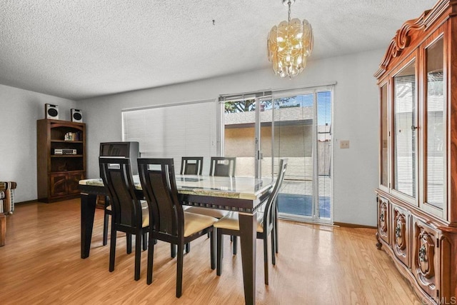 dining space featuring a textured ceiling, a chandelier, and light wood finished floors