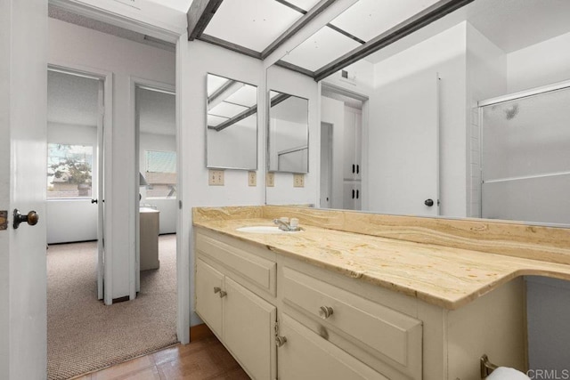 bathroom featuring a shower with shower door and vanity