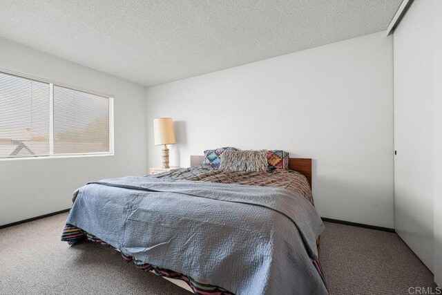carpeted bedroom with baseboards and a textured ceiling