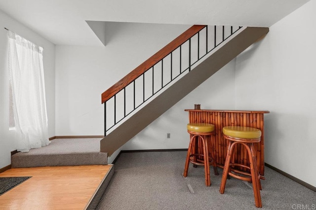 stairway featuring a bar, carpet flooring, and baseboards