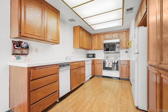 kitchen featuring white appliances, light countertops, visible vents, and light wood-style floors