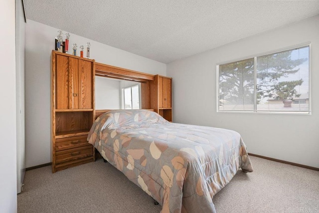carpeted bedroom featuring baseboards and a textured ceiling