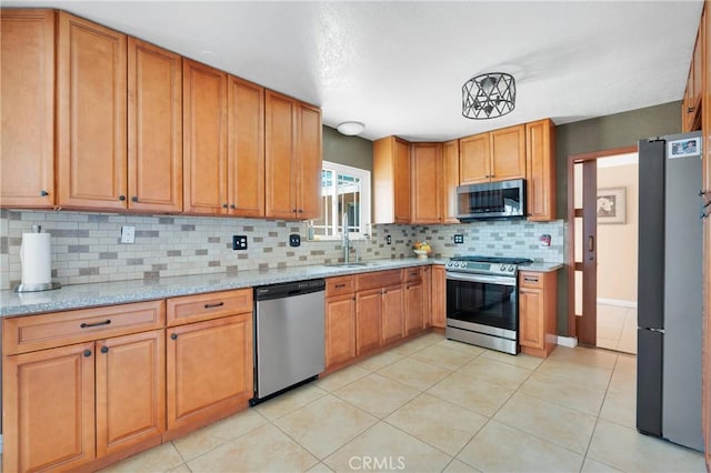 kitchen featuring light tile patterned flooring, light stone countertops, a sink, stainless steel appliances, and decorative backsplash