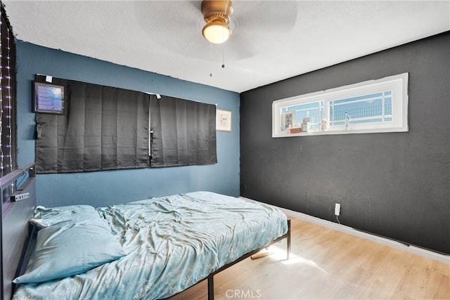 bedroom featuring baseboards, a ceiling fan, and wood finished floors