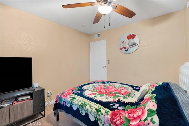 bedroom featuring baseboards, ceiling fan, wood finished floors, and visible vents