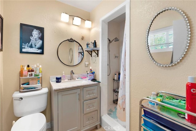 bathroom with toilet, a tile shower, and vanity