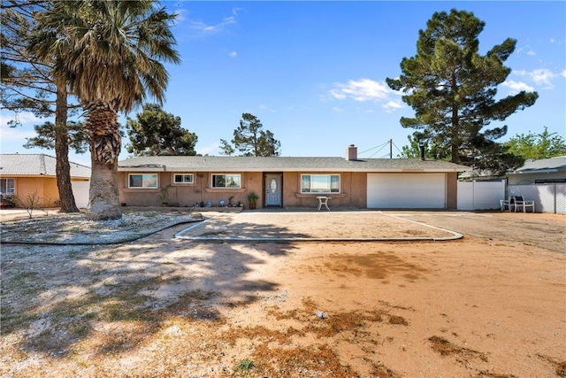 ranch-style home with an attached garage, fence, driveway, and a chimney