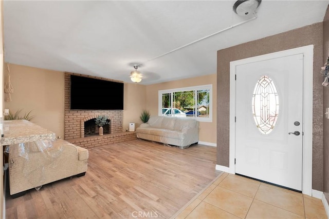 foyer with a ceiling fan, baseboards, wood finished floors, and a fireplace