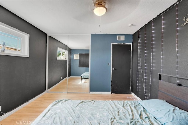 bedroom with baseboards, visible vents, and wood finished floors