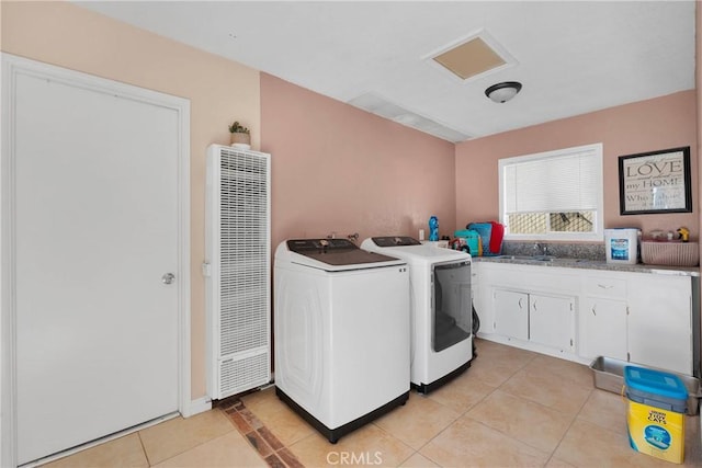 laundry room with washing machine and dryer, cabinet space, a sink, light tile patterned floors, and a heating unit