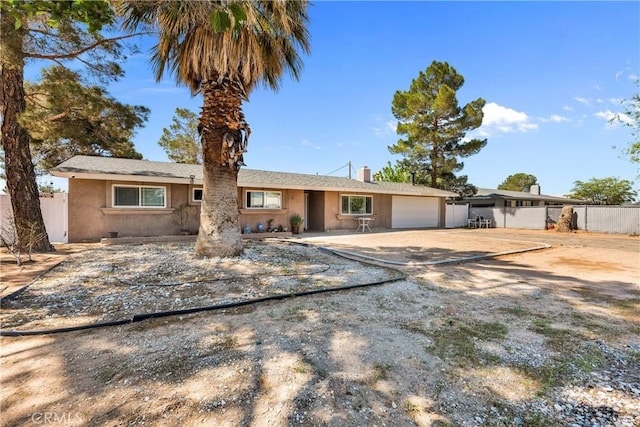 ranch-style home featuring an attached garage, fence, stucco siding, and concrete driveway