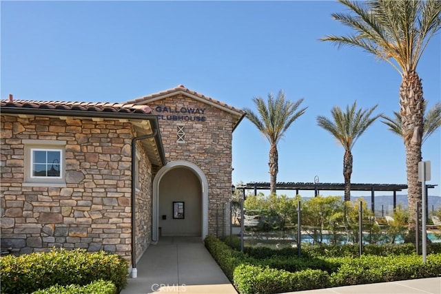 exterior space with a tiled roof and stone siding