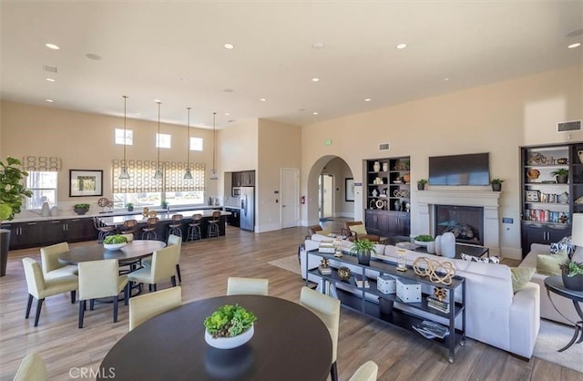 living area with visible vents, arched walkways, a fireplace, light wood-style floors, and recessed lighting