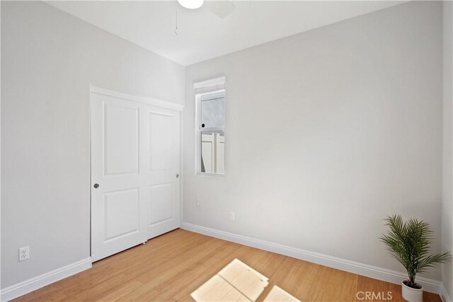interior space featuring a ceiling fan, baseboards, and light wood-type flooring