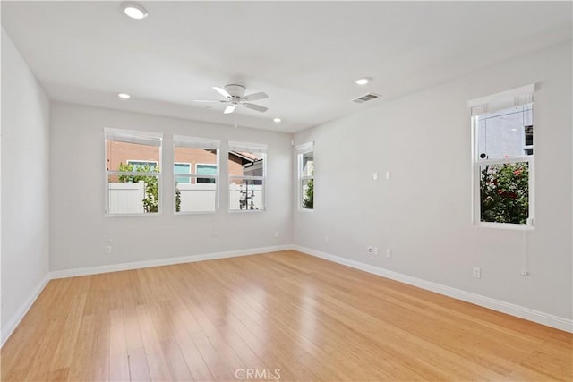 empty room featuring baseboards, a ceiling fan, light wood-type flooring, and visible vents
