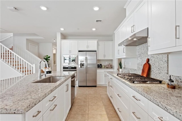 kitchen featuring visible vents, tasteful backsplash, a sink, under cabinet range hood, and stainless steel appliances