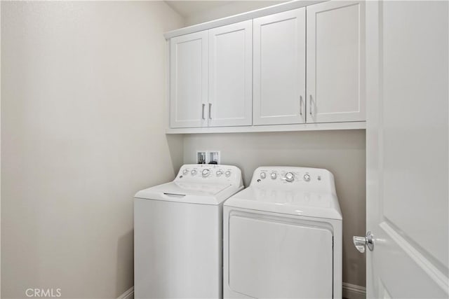 clothes washing area featuring cabinet space and washing machine and clothes dryer