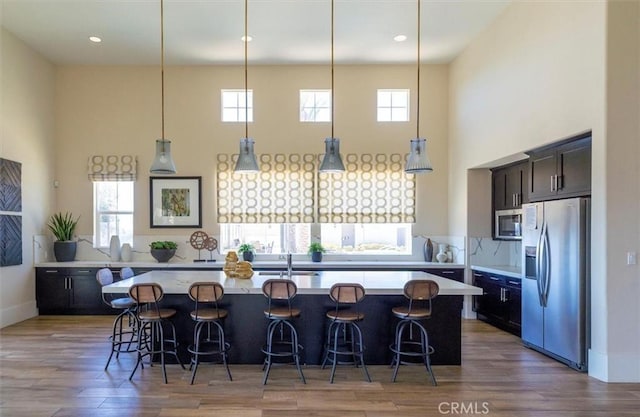 kitchen with light countertops, a kitchen breakfast bar, wood finished floors, and stainless steel appliances