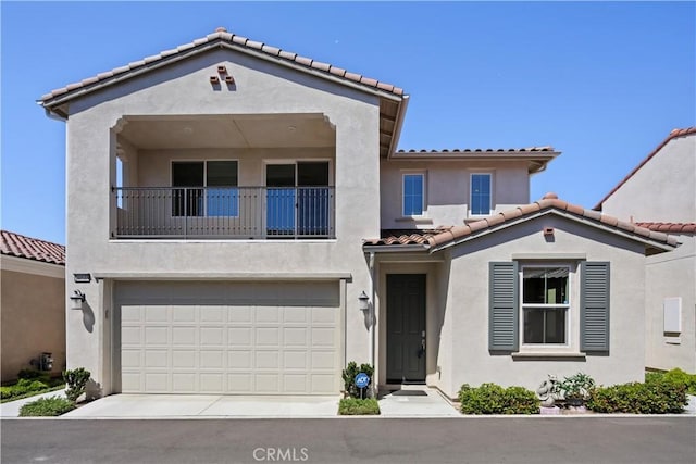 mediterranean / spanish home featuring an attached garage, stucco siding, a balcony, a tiled roof, and driveway