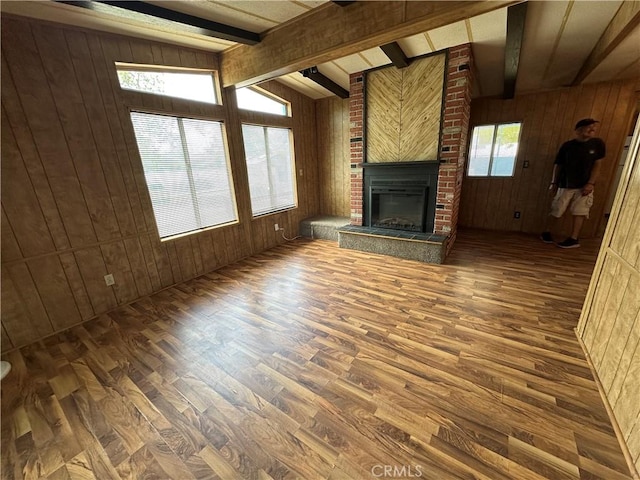 unfurnished living room with wood finished floors, wood walls, and beam ceiling