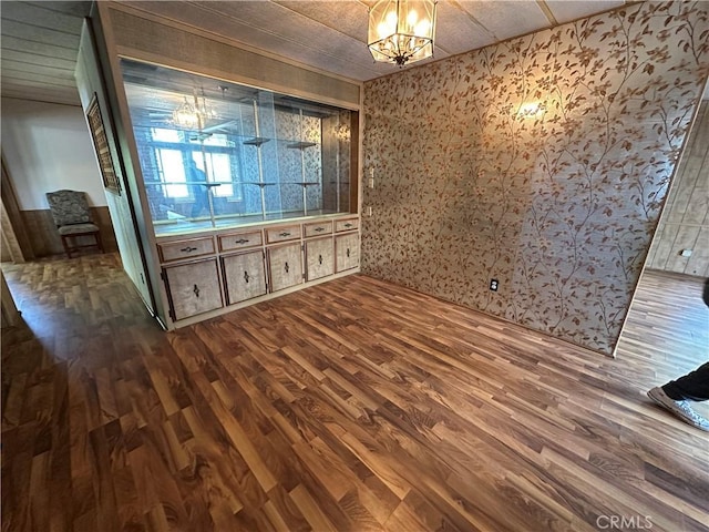 unfurnished room featuring dark wood-style flooring and a notable chandelier