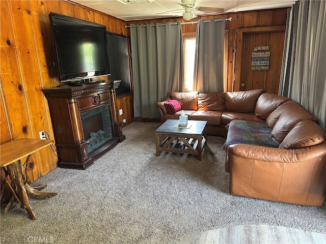 living room featuring carpet, ceiling fan, wooden walls, and a fireplace