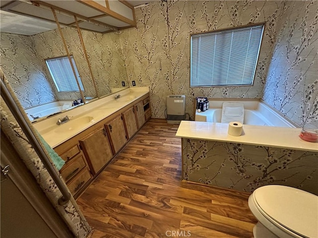 full bath with a sink, wood finished floors, toilet, and wallpapered walls