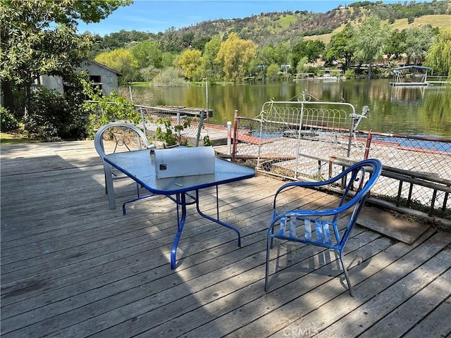 wooden terrace featuring a water view and a forest view