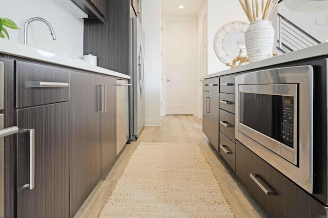 kitchen featuring a sink, modern cabinets, stainless steel appliances, and light wood-style flooring