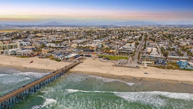aerial view at dusk with a beach view and a water and mountain view
