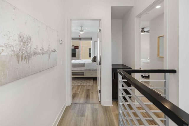 corridor featuring baseboards and light wood-style flooring